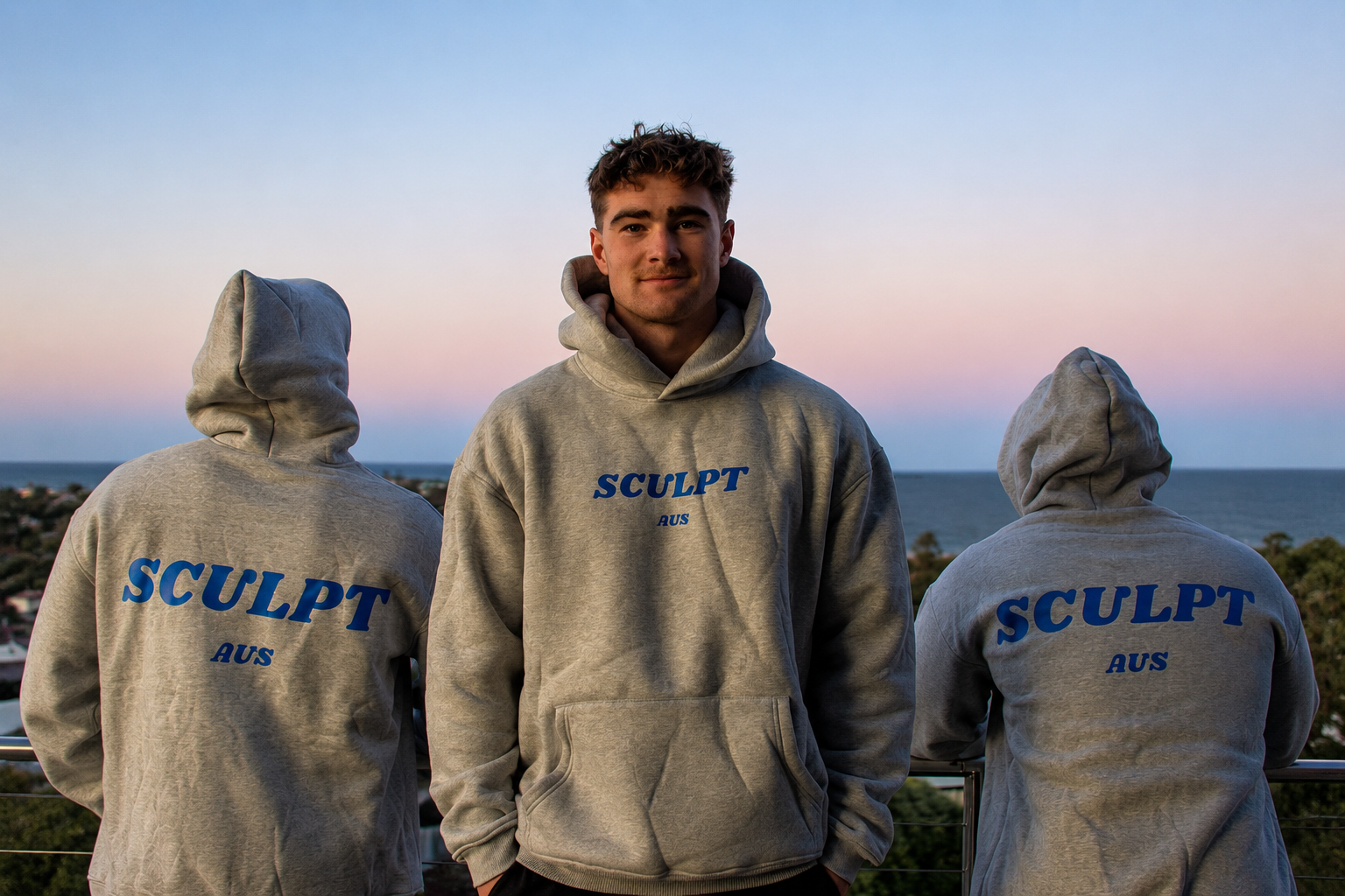 Three people wearing grey Sculpt AUS hoodies outdoors